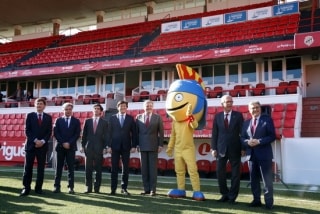 El ministre Íñigo Méndez de Vigo i la resta d&#039;autoritats fotografiant-se amb la mascota dels Jocs Mediterranis, &#039;Tarracus&#039;, a la gespa del Nou Estadi de Tarragona