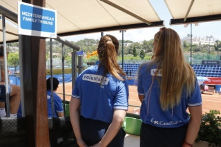 Dues voluntàries a la graderia de les pistes de tenis, d&#039;esquenes, als Jocs Mediterranis