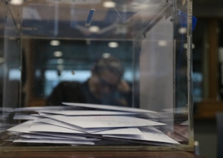 Una urna, a l&#039;oficina consular d&#039;Espanya a Brussel·les. De fons, un home esper a la sala de votació