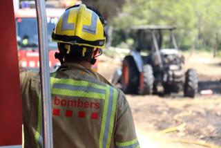 Un bomber mirant el tractor calcinat que va provocar l&#039;incendi a Mont-roig del Camp