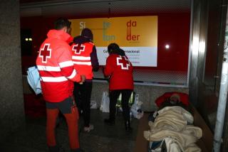 Voluntaris de la Creu Roja oferint mantes i begudes als sensesostre durant l&#039;Operació Iglú feta a la ciutat
