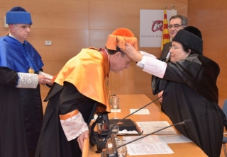 La rectora de la URV, Maria José Figueras, posant el birret al nou doctor honoris causa, l&#039;alt funcionari tarragoní de la CE, Xavier Prats