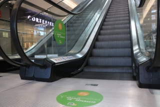Cartells a les escales màquines del centre comercial la Fira de Reus on es demana als usuaris que deixin quatre esglaons de distància