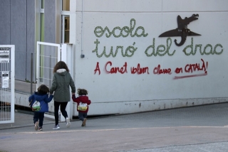 Una mare acompanya els seus fills a l&#039;escola Turó del Drac de Canet de Mar. Una pintada reclama l&#039;ensenyament en català a la façana del centre, el 9 de desembre de 2021