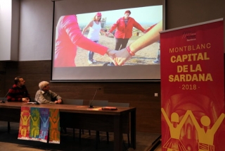 Projecció durant la presentació dels actes organitzats a Montblanc amb motiu de ser Capital de la Sardana, i del coordinador del projecte i del regidor de Cultura, observant les imatges