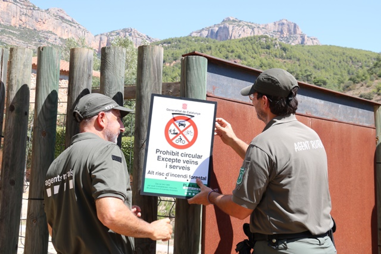 Dos agents rurals col·loquen un cartell informatiu a l&#039;accés al Parc Natural de la Serra del Montsant, des de la Cartoixa d&#039;Escaladei
