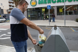 Un home llençant una bossa de brossa al contenidor de resta o rebuig en una illa de contenidors al centre de Valls, davant d&#039;un supermercat