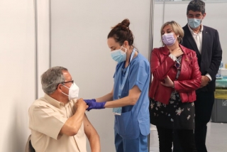 Imatge de la consellera de Salut, Alba Vergés, mirant com administren una vacuna a un home al punt de vacunació massiva del Palau d&#039;Esports Catalunya de Tarragona