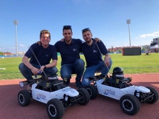 Els tres estudiants amb els vehicles creats per recollir el material d&#039;atletisme dels Jocs Mediterranis