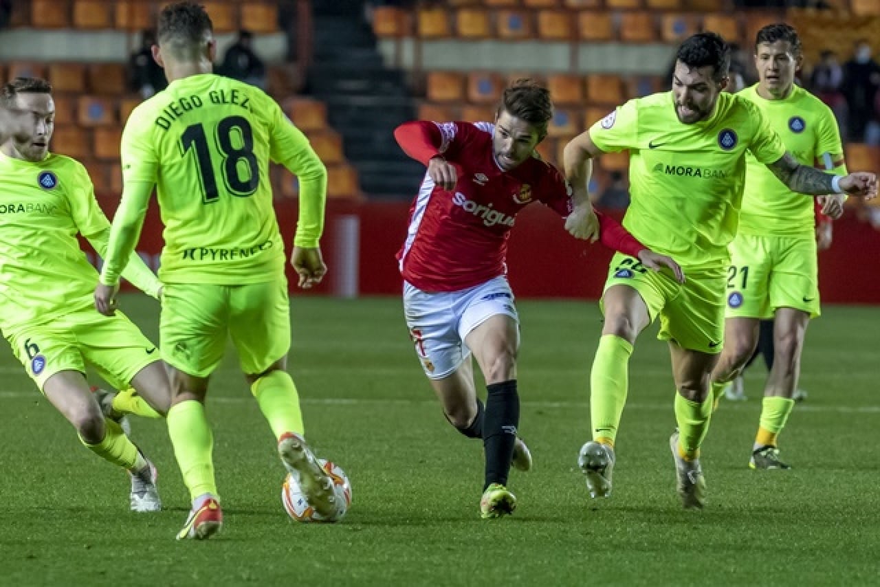 El jugador del Nàstic Fran Carbia lluita una pilota amb els jugadors de l&#039;Andorra, en el `partit disputat al Nou Estadi