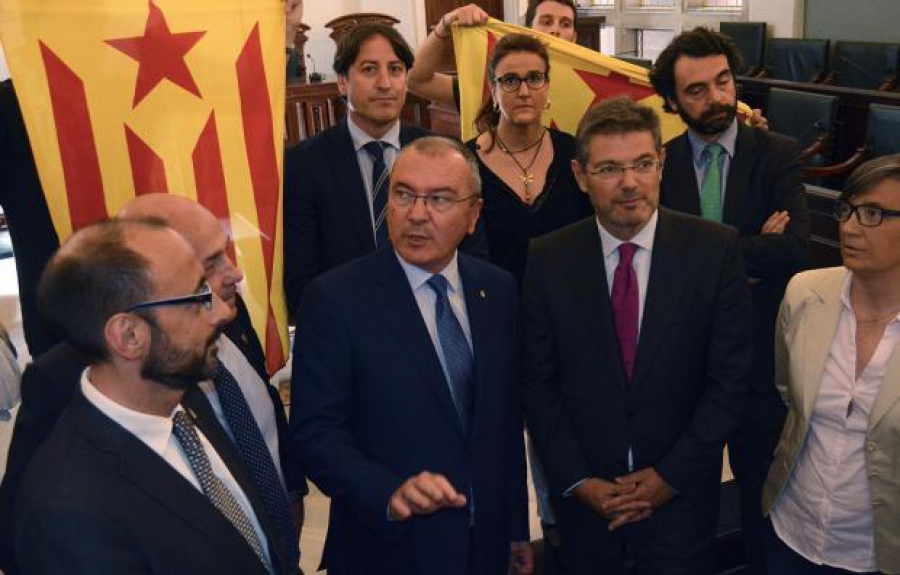El Ministre de Justícia, Rafael Català, amb les estalades de fons que portaven els regidors de la CUP.