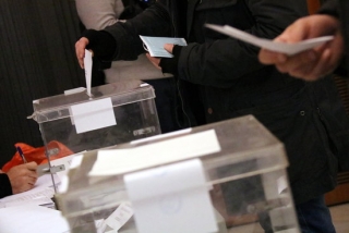 Una mà diposita un vot en una urna, amb una segona urna en primer pla, el 21 de desembre de 2017