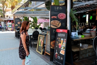Una dona mira l&#039;oferta gastronòmica d&#039;un restaurant situat al passeig marítim de Salou