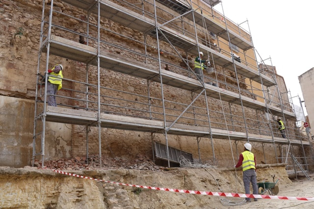 Operaris treballant en la recuperació de l&#039;antiga muralla de Sant Antoni de Valls, on s&#039;ha instal·lat una gran bastida
