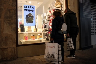 Dos compradors amb bosses de comprar mirant un aparador d&#039;una botiga del centre de Reus, en el primer cap de setmana de la campanya de Nadal