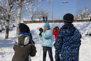 Una nena està a punt de llançar una bola de neu als seus companys, mentre juguen al pati de l&#039;escola Guillem de Mont-Rodon de Vic