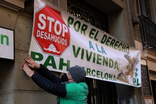 Un activista col·locant una pancarta contra els desnonaments en un edifici de Barcelona