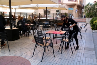Imatge d&#039;arxiu d&#039;una cambrera netejant una taula en la terrassa mig buida de la Cafeteria Vips de Tortosa, el 6 d&#039;octubre del 2020