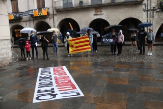 Imatge dels assistents a la concentració gironina en contra de la regressió de drets i llibertats amb paraigües sota la pluja 