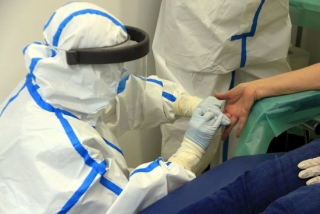 Professionals del CAP Manso, amb equip de protecció individual (EPI), en el moment d&#039;extreure una mostra de sang amb una punxada al dit a una participant a l&#039;estudi de seroprevalença del coronavirus a nivell estatal