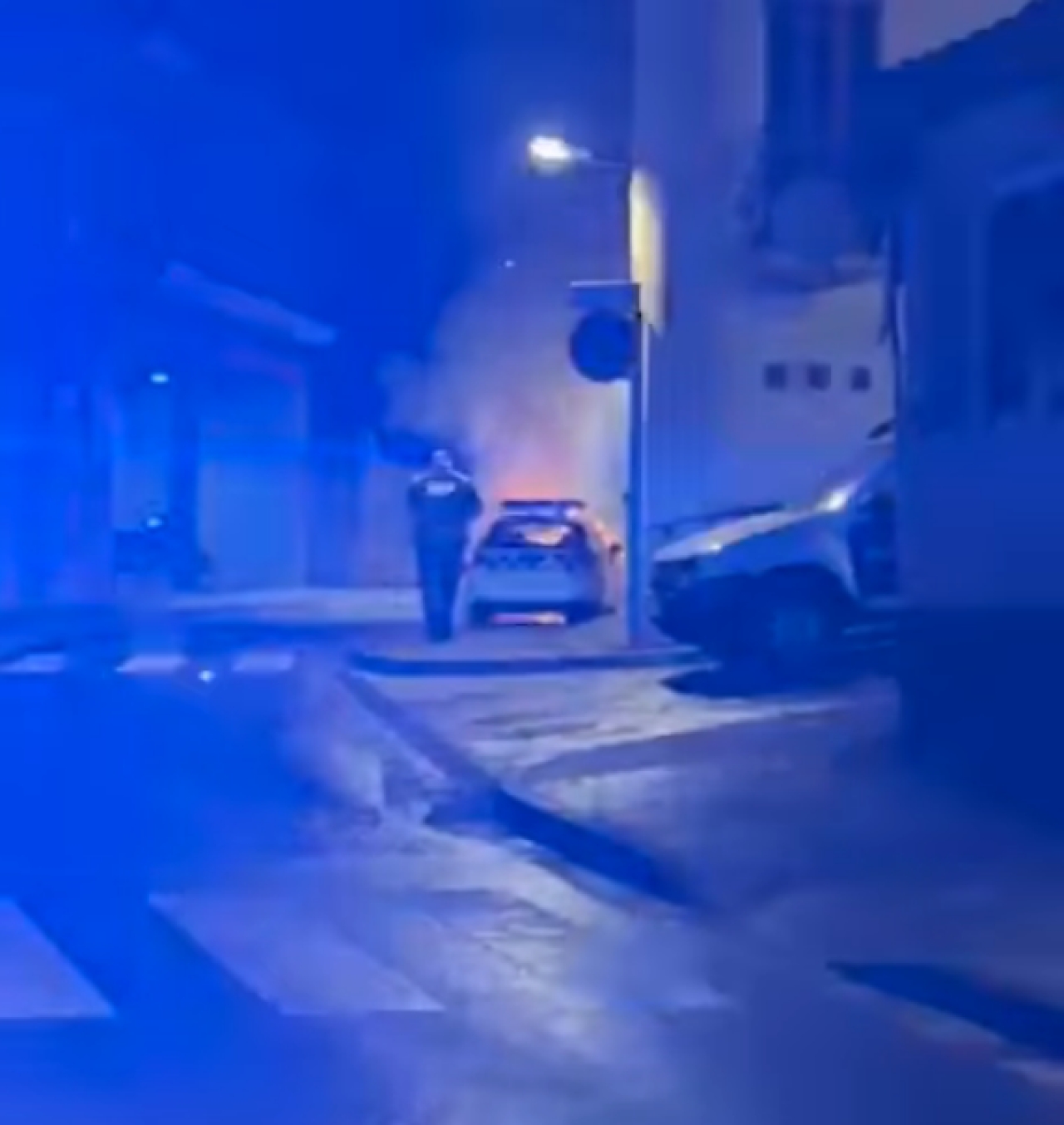 Imatge captada pel veïnat d&#039;un agent intentant apagar el foc en un cotxe de la Policia Local de Valls, aquest dilluns a la nit