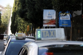 Una filera de taxis buits esperant en una parada de Tarragona, amb una banderola dels Jocs Mediterranis penjada a la zona