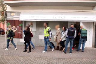 Agents de la Guàrdia Civil i de la policia espanyola sortint d&#039;uns dels establiments escorcollats amb una dona detinguda en l&#039;operació feta a Torredembarra