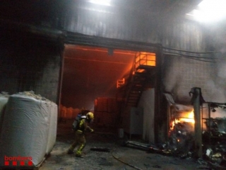 Imatge de l&#039;incendi que va cremar en una indústria de pinsos de Puigpelat (Alt Camp) i de bombers treballant-hi per apagar el foc