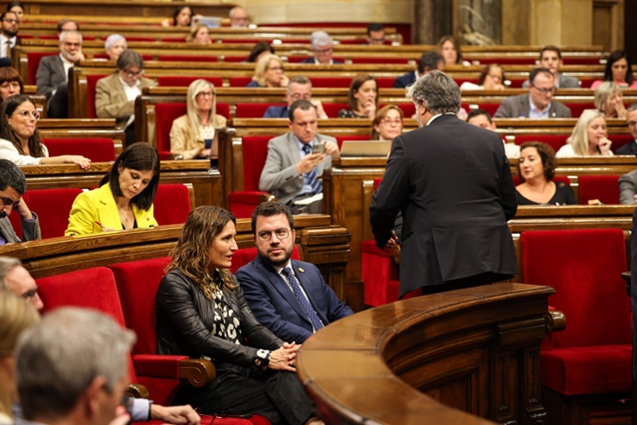 El president de Junts, Albert Batet, d&#039;esquenes, torna al seu escó amb el president de la Generalitat, Pere Aragonès, assegut