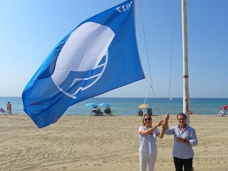 L’alcalde de Roda de Berà, Pere Virgili, i la regidora de Platges, Isabel Mondéjar hissant una de les Banderes Blaves 