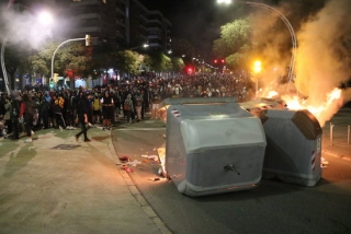 La cantonada de la plaça Imperial Tarraco amb Marquès de Montoliu, a Tarragona, amb un contenidor en flames i un grup de manifestants al darrere