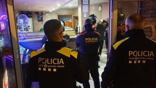 Un detingut i agents de la Guàrdia Urbana i Mossos d&#039;Esquadra, d&#039;esquenes, en l&#039;operatiu policial conjunt fet en dos locals de Reus