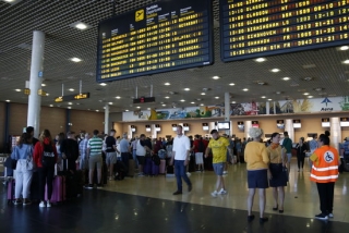 Imatge de cues per facturar a l&#039;Aeroport de Reus i del panell informatiu que indica retards en els vols amb destinació al Regne Unit que operava la companyia Thomas Cook