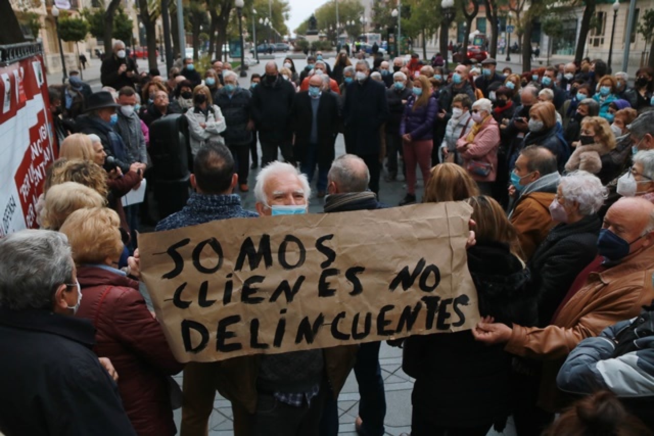 Un protestant mostra una pancarta en què critica el tracte rebut per part de la banca durant la concentració a Tarragona