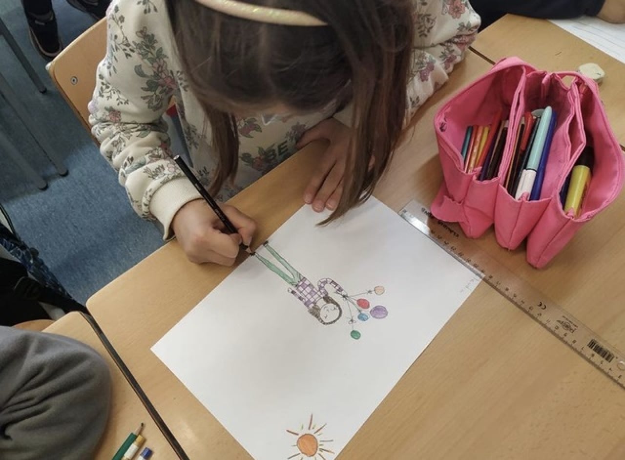 Una nena fa un dibuix, després de veure el vídeo sobre el Centre de Dia per a Gent Gran Marinada