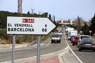 Les cues a l&#039;N-340 a Roda de Berà, amb un cartell en primer terme on s&#039;hi pot llegir que falten 6 km per arribar al Vendrell i 68 km per arribar a Barcelona. 