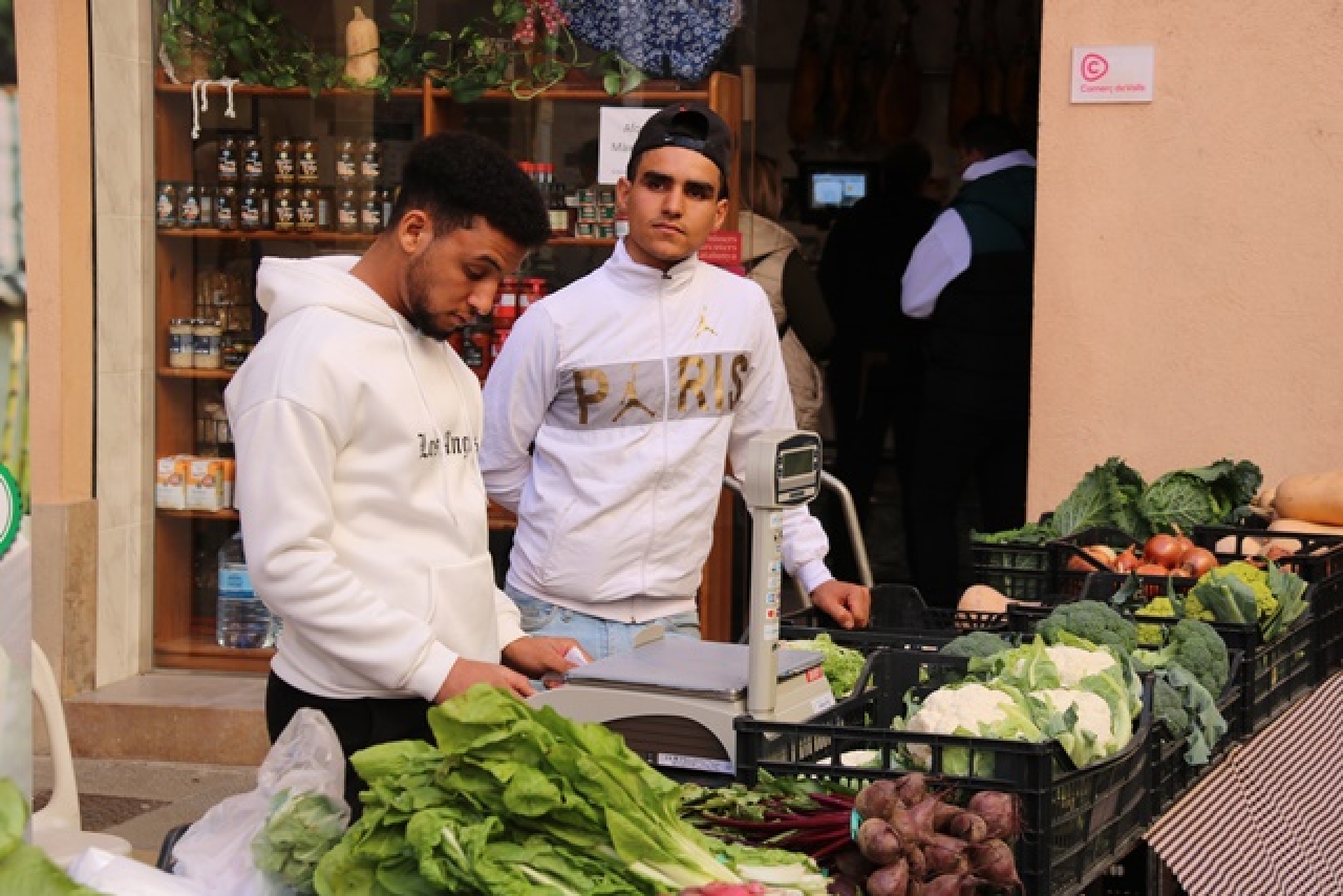 Joves extutelats al mercat de Valls venent verdures que han conreat ells mateixos en una finca del municipi 